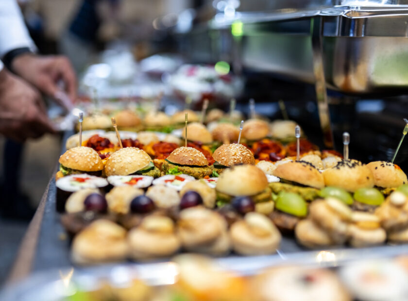 Assorted appetizers and gourmet sliders displayed at a catered event in an elegant venue during evening hours